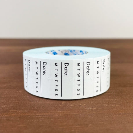 Stamp Marche Planner Label Sticker Roll - Date and Days of the Week Roll of tape with date and day-of-week markings on a wooden surface
