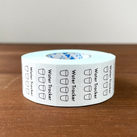 Stamp Marche Planner Label Sticker Roll - Water Tracker Roll of water tracker labels on a wooden surface