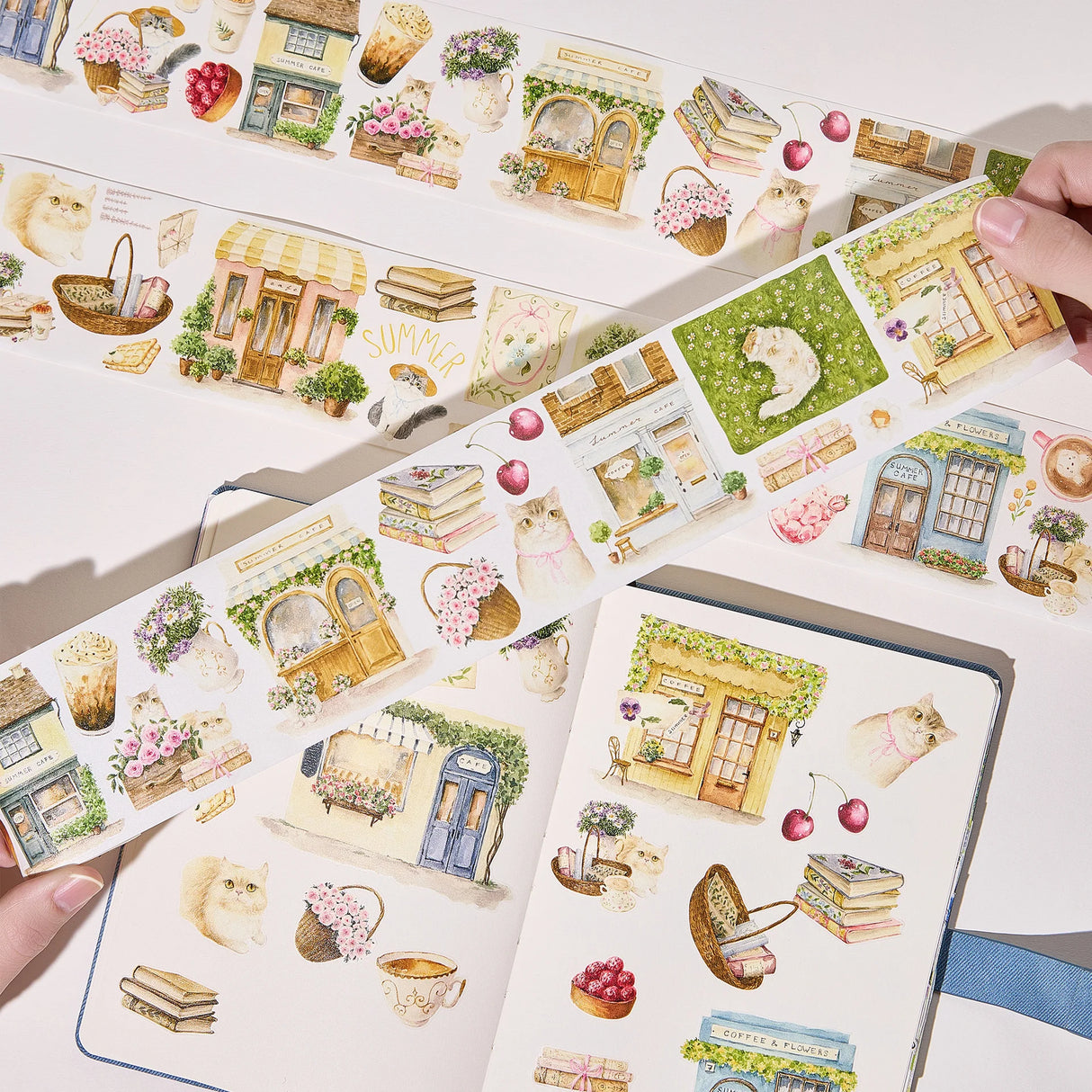 Step into a world where nature and comfort collide. Our Summer Café Wide Tape transforms your stationery into a bustling garden bistro, teeming with life, blooming flowers, and the true owners of the cafe: the cats.

This whimsical design weaves together the architecture of charming coffee shops with the wild beauty of summer florals. Nestled among the potted plants and open doors, you’ll find hand-painted cats exploring, sleeping, and playing.&nbsp;

