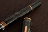 This TWSBI Obsidian fountain pen is made of a dark grey/black swirled acrylic resin, inspired by the natural obsidian stone. The pen is complemented by rose gold-plated trim and is equipped with a rose gold-plated stainless-steel nib.

Pen cap is&nbsp;able to post&nbsp;onto the back of the pen

Piston Filler Fountain pen.
Simply unscrew the end cap, dip into ink, screw back the end cap, and you're done! Ready to write!!