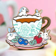 These pastel bunnies are spending a relaxing day amongst blueberries, cherries, and yummy tea inside an intricately decorated cup.

✦ Hard enamel
✦ Shiny gold metal
✦ 1.75 inches
✦ 2 Posts for extra security
✦ Rubber backings
✦ Back stamped for authenticity

Comes packaged on a backing card.