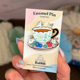 These pastel bunnies are spending a relaxing day amongst blueberries, cherries, and yummy tea inside an intricately decorated cup.

✦ Hard enamel
✦ Shiny gold metal
✦ 1.75 inches
✦ 2 Posts for extra security
✦ Rubber backings
✦ Back stamped for authenticity

Comes packaged on a backing card.