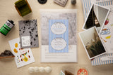 Collection of stationery items including notebooks, postcards, and a photo album on a wooden surface.