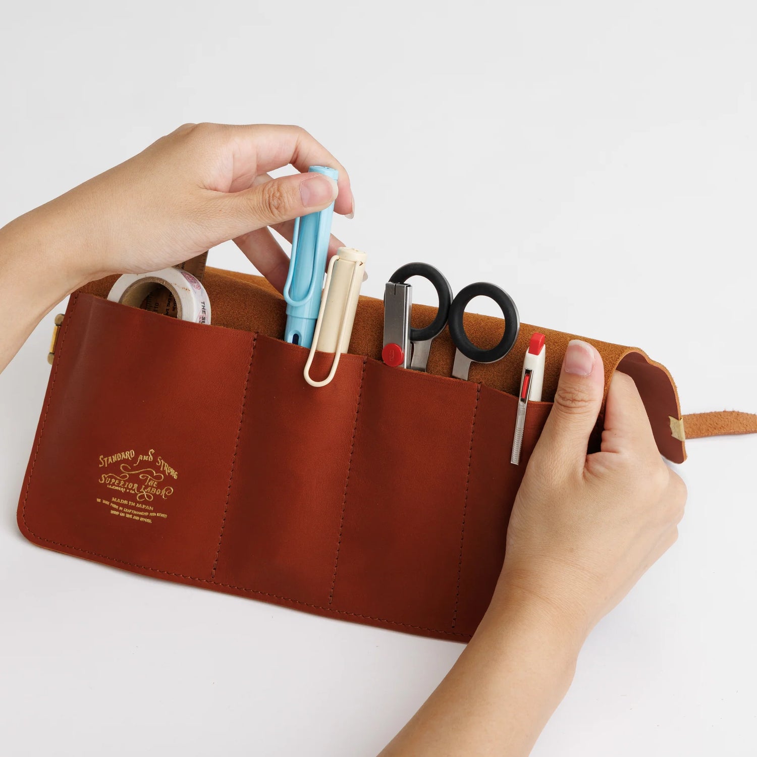 The SUPERIOR LABOR Glove Leather - Roll Pen Case

The discontinued&nbsp;pen roll&nbsp;has returned with a refined new design.&nbsp;A brass tag accents its raw-cut edge, while the logo inside is finished with elegant gold foil.&nbsp;The result is a fresh look that feels both light and sophisticated.

Pockets in varying sizes hold pens of different types, and when you’re done, simply roll it up and take it with you.

A pen case that combines the joy of displaying your favorite pens with the practicality of ca