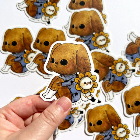 The puppy and flower vinyl sticker was illustrated by jb0xtchi (Jessica Ng). jb0xtchi creates stationary and small trinkets from whimsical ideas in the form of painting using ink, watercolour, and gouache.

Height: 70mm x Width: 60mm
Matte clear laminate coating
100% weatherproof (UV, Water etc)
Scratch resistant &amp; long lasting
Includes 1 sticker&nbsp;