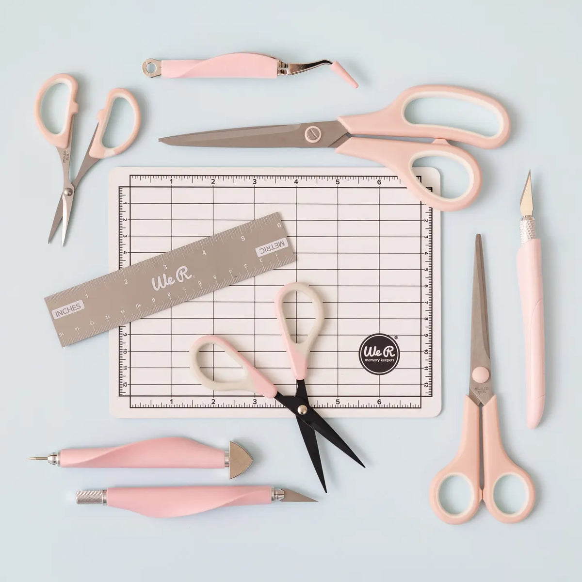 The We R Makers Mini Tool Kit in Pink is the ultimate companion for all your DIY craft projects. This comprehensive kit includes essential tools: a cutting mat, ruler, scissors, craft knife, tweezers, brad setter, and piercing tool. Designed for versatility, it's perfect for scrapbooking, journaling, card making, and a wide range of other crafts.

The vibrant pink color adds a fun and stylish touch to your toolkit, while the high-quality construction ensures each tool is durable and reliable. The cutting ma