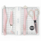 The We R Makers Mini Tool Kit in Pink is the ultimate companion for all your DIY craft projects. This comprehensive kit includes essential tools: a cutting mat, ruler, scissors, craft knife, tweezers, brad setter, and piercing tool. Designed for versatility, it's perfect for scrapbooking, journaling, card making, and a wide range of other crafts.

The vibrant pink color adds a fun and stylish touch to your toolkit, while the high-quality construction ensures each tool is durable and reliable. The cutting ma