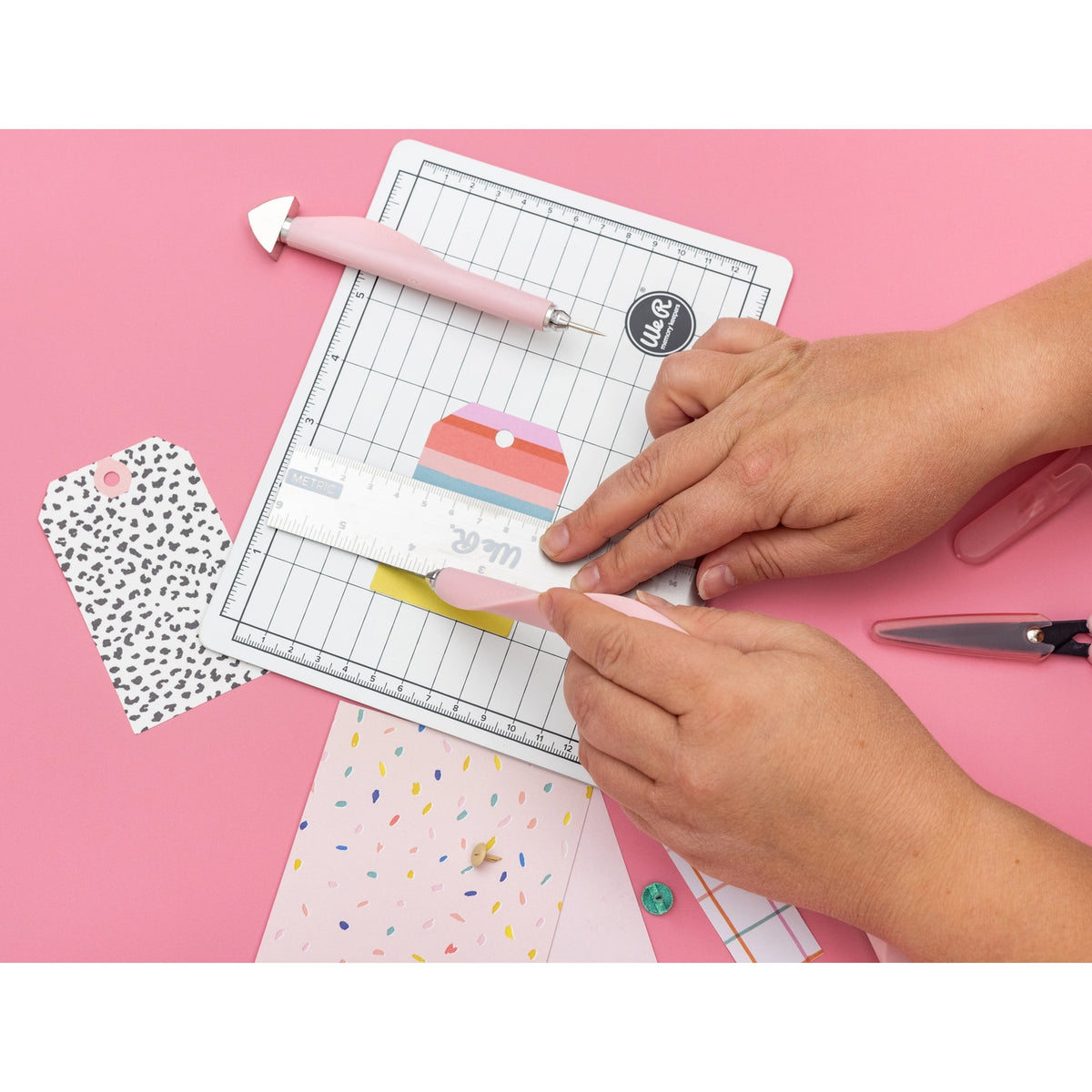 The We R Makers Mini Tool Kit in Pink is the ultimate companion for all your DIY craft projects. This comprehensive kit includes essential tools: a cutting mat, ruler, scissors, craft knife, tweezers, brad setter, and piercing tool. Designed for versatility, it's perfect for scrapbooking, journaling, card making, and a wide range of other crafts.

The vibrant pink color adds a fun and stylish touch to your toolkit, while the high-quality construction ensures each tool is durable and reliable. The cutting ma